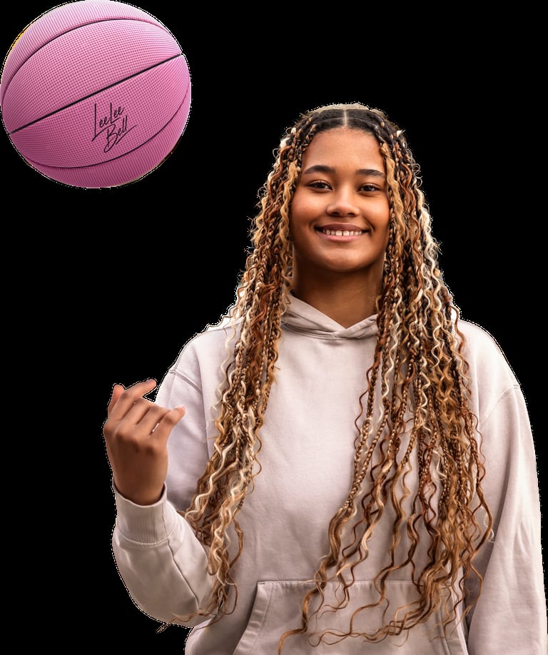 Smiling young woman with long braided hair in white hoodie, spinning a pink basketball